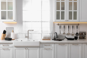 Set of different utensils near sink on countertop in kitchen