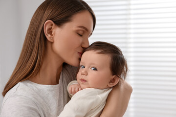 Fototapeta na wymiar Happy mother kissing her little baby indoors