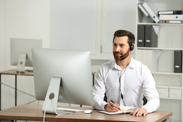 Fototapeta na wymiar Hotline operator with headset working in office
