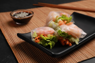 Tasty spring rolls served with soy sauce on grey table, closeup