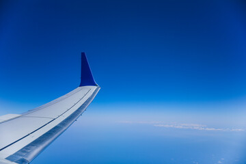 aerial view from a window seat captures the majestic airplane wing soaring through the clouds, symbolizing freedom, adventure, and travel. The view offers a sense of perspective
