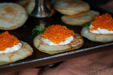 Tasty appetizer for dinner, small pancakes bliny with red fish caviar and sour cream