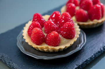 Artisanal baked small tart with cream and fresh ripe red raspberry
