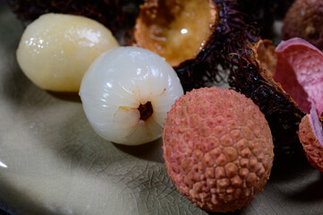 Tasty tropical exotic fruits, ripe fresh peeled and unpeeled lychee and hairy rambutan southeast Asian fruits  rambutan southeast Asian fruits