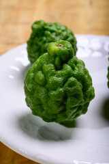 kaffir lime or makrut lime, citrus fruit native to tropical Southeast Asia. Fruit and leaves used in Southeast Asian cuisine, essential oil is used in perfumery for intense citrus fragrance.