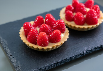 Artisanal baked small tart with cream and fresh ripe red raspberry