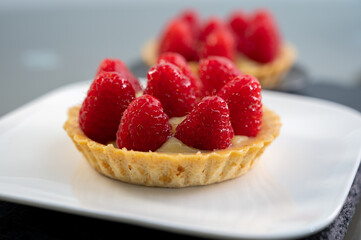 Artisanal baked small tart with cream and fresh ripe red raspberry