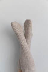 Photo of a pair of women's socks being worn by a caucasian woman. Her feet are posing up against the wall. 