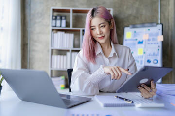 Young Asian accountant working in a financial office Manage sales reports using calculator with laptop and financial documents.