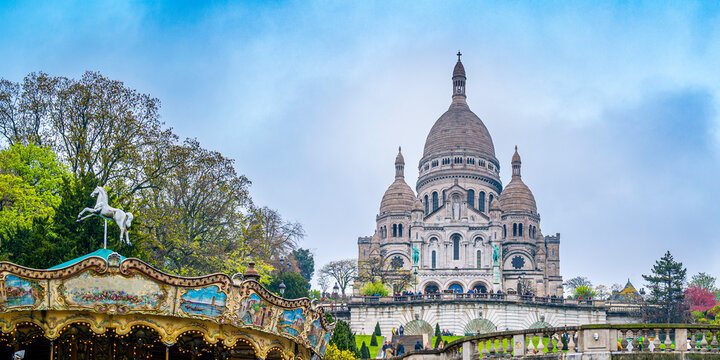 Paris skyline over the Sacre Coeur Basilica or Basilique Du Sacre Coeur and the hill of Montmartre, vibrant spring colors of the woodland and the sky in France