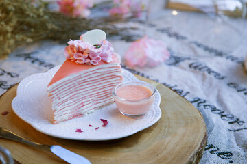 Sakura crepe cake on a plate lined with a wooden tray