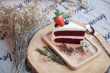 Red Velvet Cake Cream cake with topping strawberries on a wooden plate lined with a wooden tray