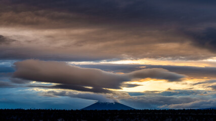 A dramatic sunset over the Cascade Mountains in Central Oregon creates a dramatic sky and clouds outside of Bend Oregon