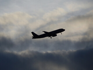 Fototapeta na wymiar silueta de un avion comercial de color negro con nubes de fondo