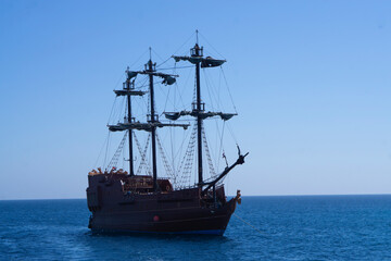 Old ancient pirate ship on peaceful ocean at sunny day. Pirate ship at the open sea with copy space and selective focus in Egypt red sea.