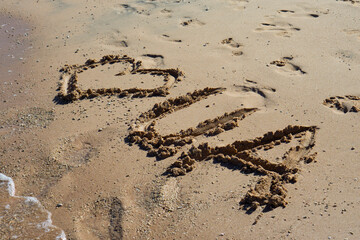 Heart drawn in the sand. Beach background. Top view, selective focus.