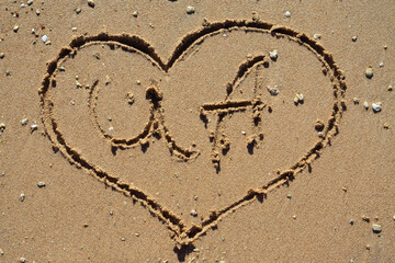Heart drawn in the sand. Beach background. Top view, selective focus.