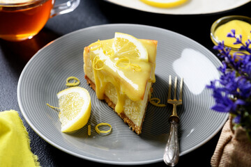 Slice of fresh baked homemade lemon cheesecake with lemon curd and lemon slices.