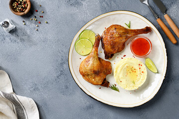 Freshly roasted duck legs confit served with potato puree and lime slices. top view