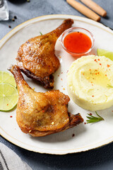Freshly roasted duck legs confit served with potato puree and lime slices.