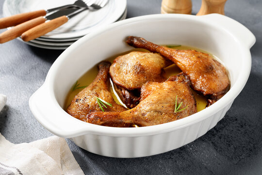 Freshly roasted duck legs confit in oven pan.