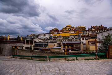 Fototapeta na wymiar Ganden Sumtseling monastery main buildings scenic view with golden roofs surrounded by green nature in Shangri-La Yunnan China