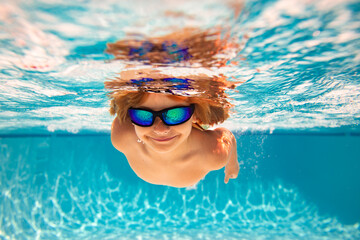 Fototapeta premium Child in swimming in pool. Funny little boy swims underwater in the pool. Underwater kids portrait from under the water. Summer holiday. Kids weekend.