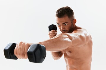 Man athletic body bodybuilder posing with dumbbells with naked torso abs full-length in the background, fitness class. Advertising, sports, active lifestyle, competition, challenge concept. 