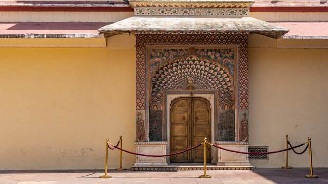 Details of the design of the ancient City Palace. The patterned doors are framed with beautiful paintings in the form of a peacock's tail, flowers, and images of people. India. Jaipur