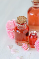 Concept of perfume with pure natural organic rose ingredient, essential oils. Glass bottles with flower herbal extract and elixir. Perfumery cosmetic toilet water fragrance, cream, skin care product