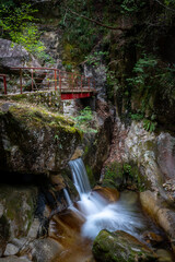 Beautiful and serene waterfall with red foot bridge at Jakuchi Gorge, Goryu Falls, 7 falls hike in Iwakuni, Yamaguchi prefecture, Japan.