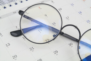 Black eyeglasses on calendar page close up. Planning business concept.