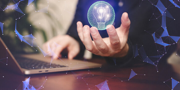 Businessman using laptop with glowing light bulb on blurry background. Idea concept