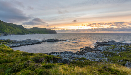 Wonderful sunset above the sea  on Runde island with fresh grass in the foreground and mountains in...