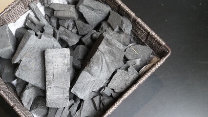 Natural wood charcoal traditional charcoal or hard wood charcoal on wooden table top view. Charcoal material for igniting fire for a grill or cooking outdoor party. Black charcoal close up top view.