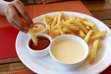 Person dipping french fries in ketchup