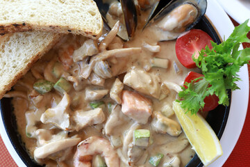 Various seafood stewed in creamy sauce in frying pan