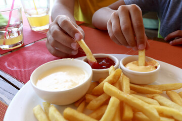 People dipping french fries in various sauces