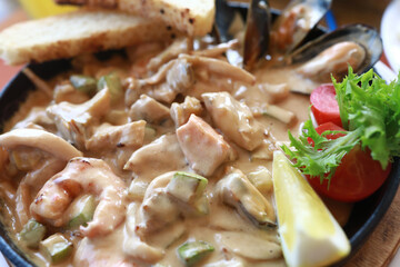 View of seafood stewed in creamy sauce in frying pan