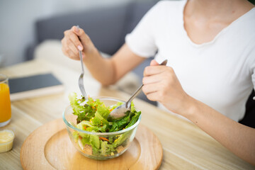 Happy beautiful Asian woman eating healthy food with vegan.salad in the kitchen at home.