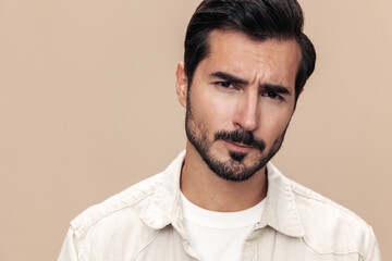 Portrait of a stylish man dissatisfied and angry screaming on a beige background in a white t-shirt looking at the camera, fashionable clothing style, copy space, space for text