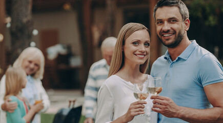 Happy young couple embracing while enjoying time with family outdoors