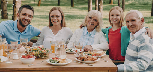 Happy multi-generation family embracing while enjoying dinner outdoors together