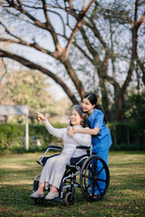 Elderly asian senior woman on wheelchair with Asian careful caregiver.