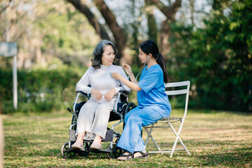 Fototapeta premium Elderly asian senior woman on wheelchair with Asian careful caregiver. Nursing home hospital garden