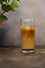 Tasty ice coffee with milk, cold drink in glass in dark background.