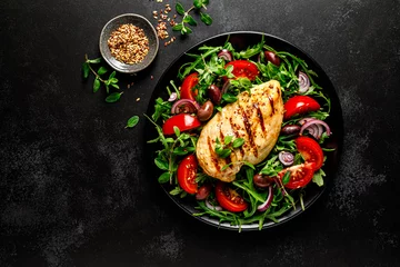  Chicken breast fillet grilled and fresh vegetable green salad with arugula, tomatoes and olives on black background, healthy food, mediterranean diet, top view © Sea Wave