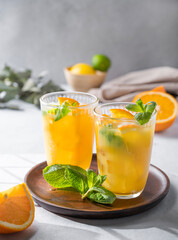 Freshly squeezed juice with fresh oranges, mint and ice on a light background. Healthy citrus detox drink for breakfast.