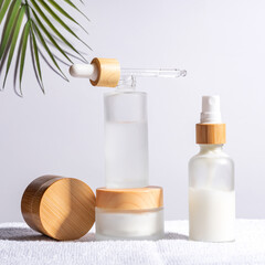 Bamboo cream jar and dropper bottle with face oil on a white background. Cosmetic container mockups. Background for branding and packaging presentation. Natural skincare beauty product concept.