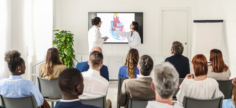 A team of Asian doctors illustrates results of their research conducted on the human heart. The audience consists of other medical specialists and major representatives of pharmaceutical companies. 